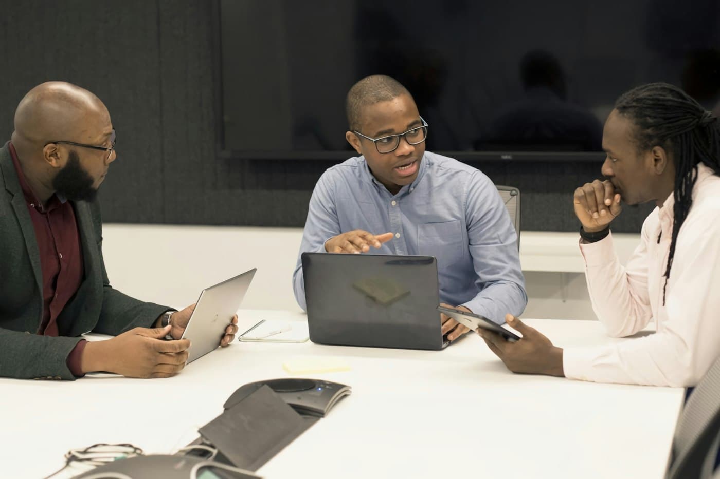 A team meeting around a conference table with laptops